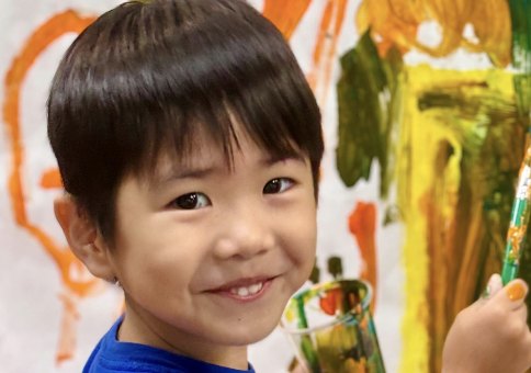 Niño sonriendo mientras pinta un mural