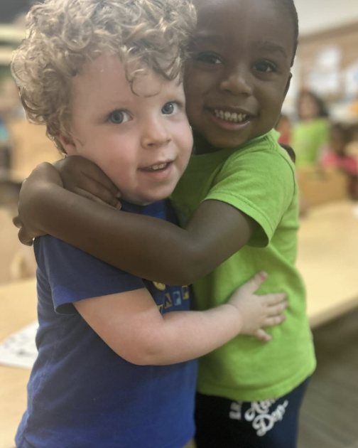 Dos niños de Tiniciti abrazándose y sonriendo en el salón