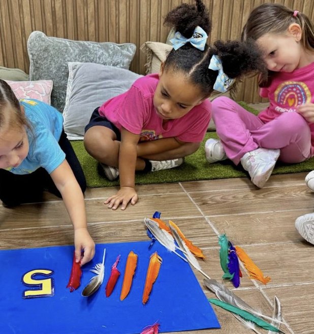 Niñas contando plumas de colores junto al número 5